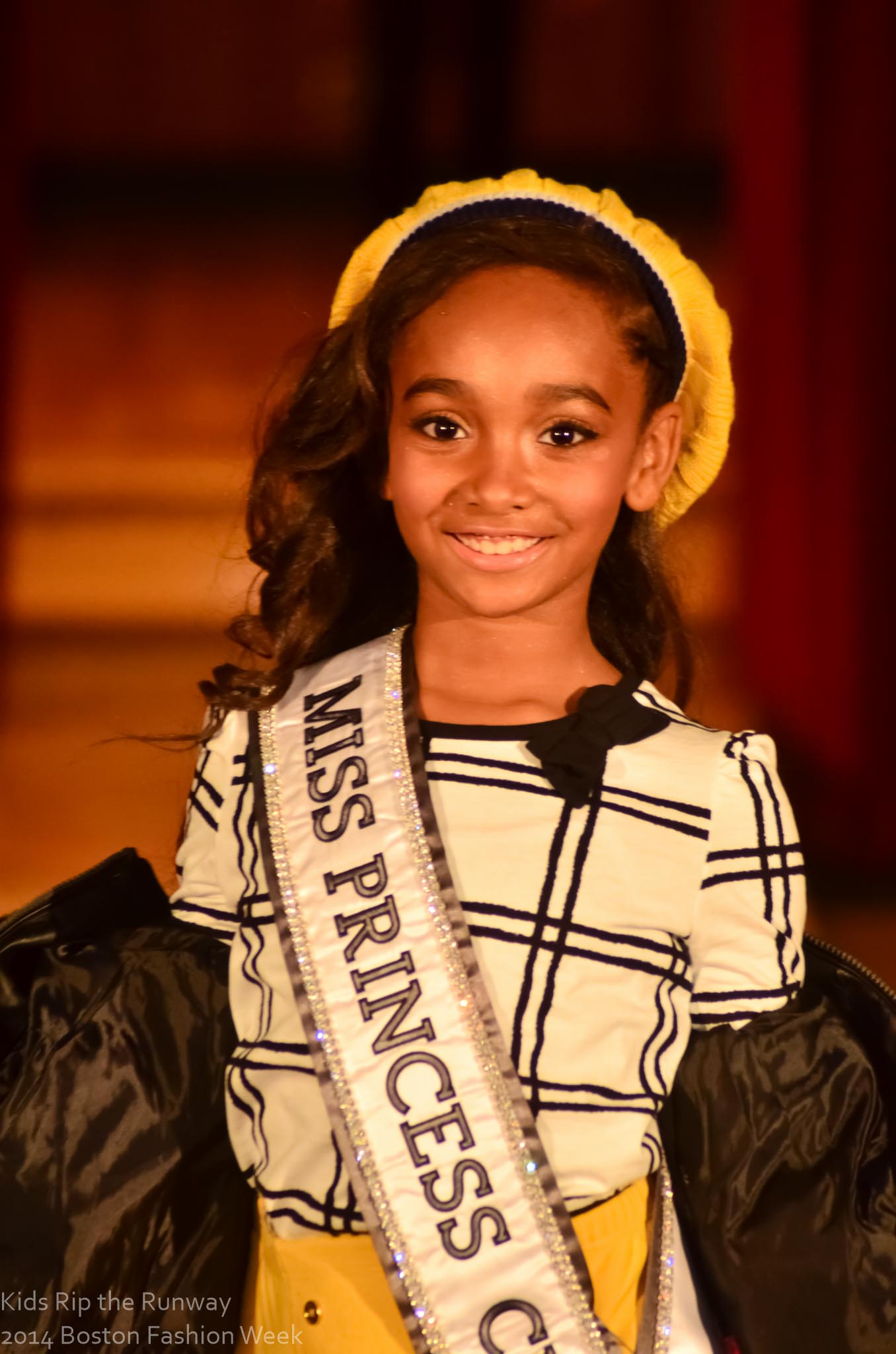 A smiling young participant wearing her Miss Princess sash at Kids Rip the Runway.